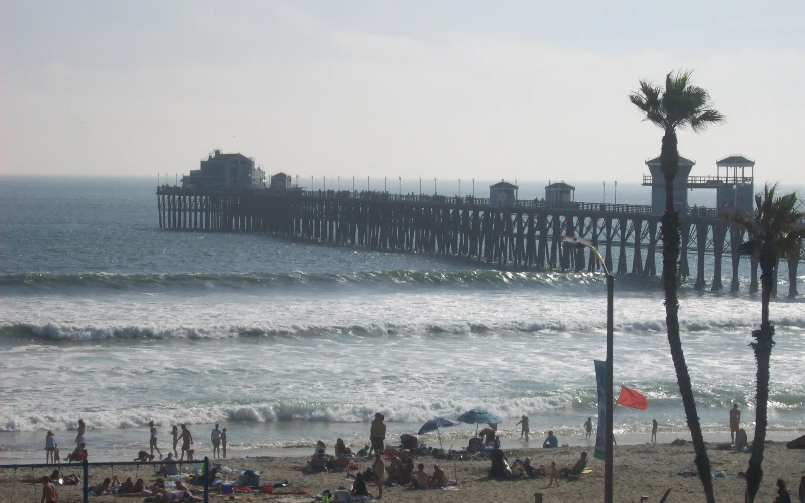 The Oceanside Pier extending into the Pacific Ocean, photographed on a clear day with the California coastline visible
