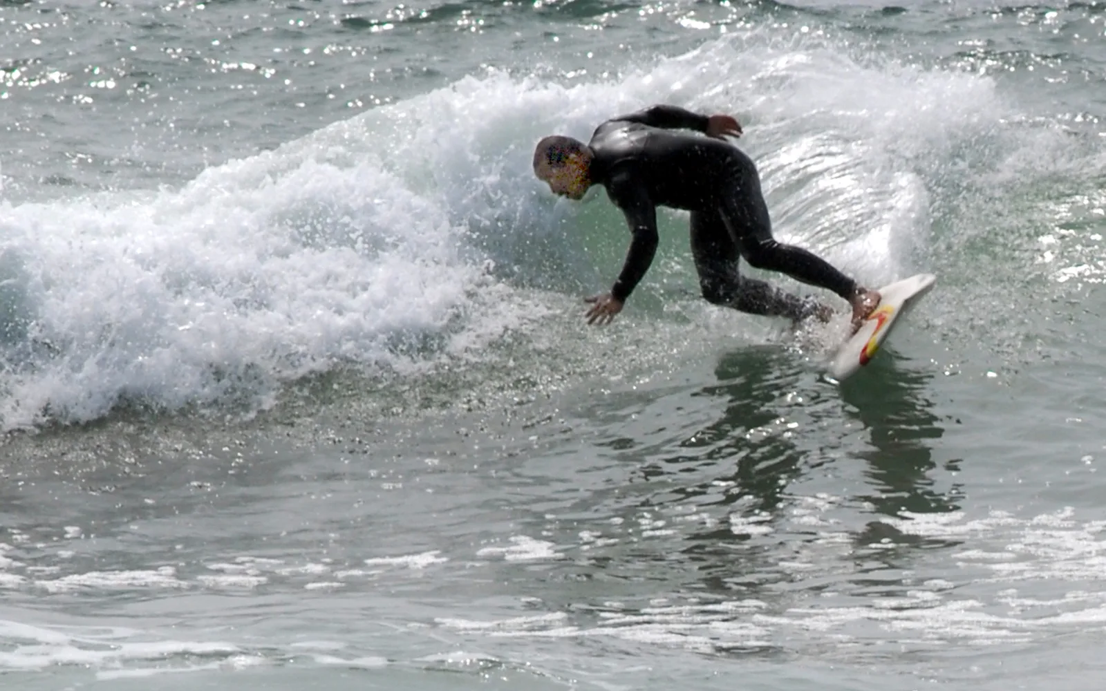 A surfer in California waters with surfboard, demonstrating the sport that the California Surf Museum celebrates
